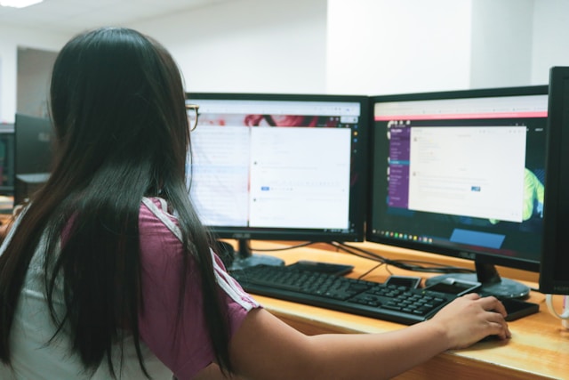Sekretářka pracující na počítači s dvěma monitory